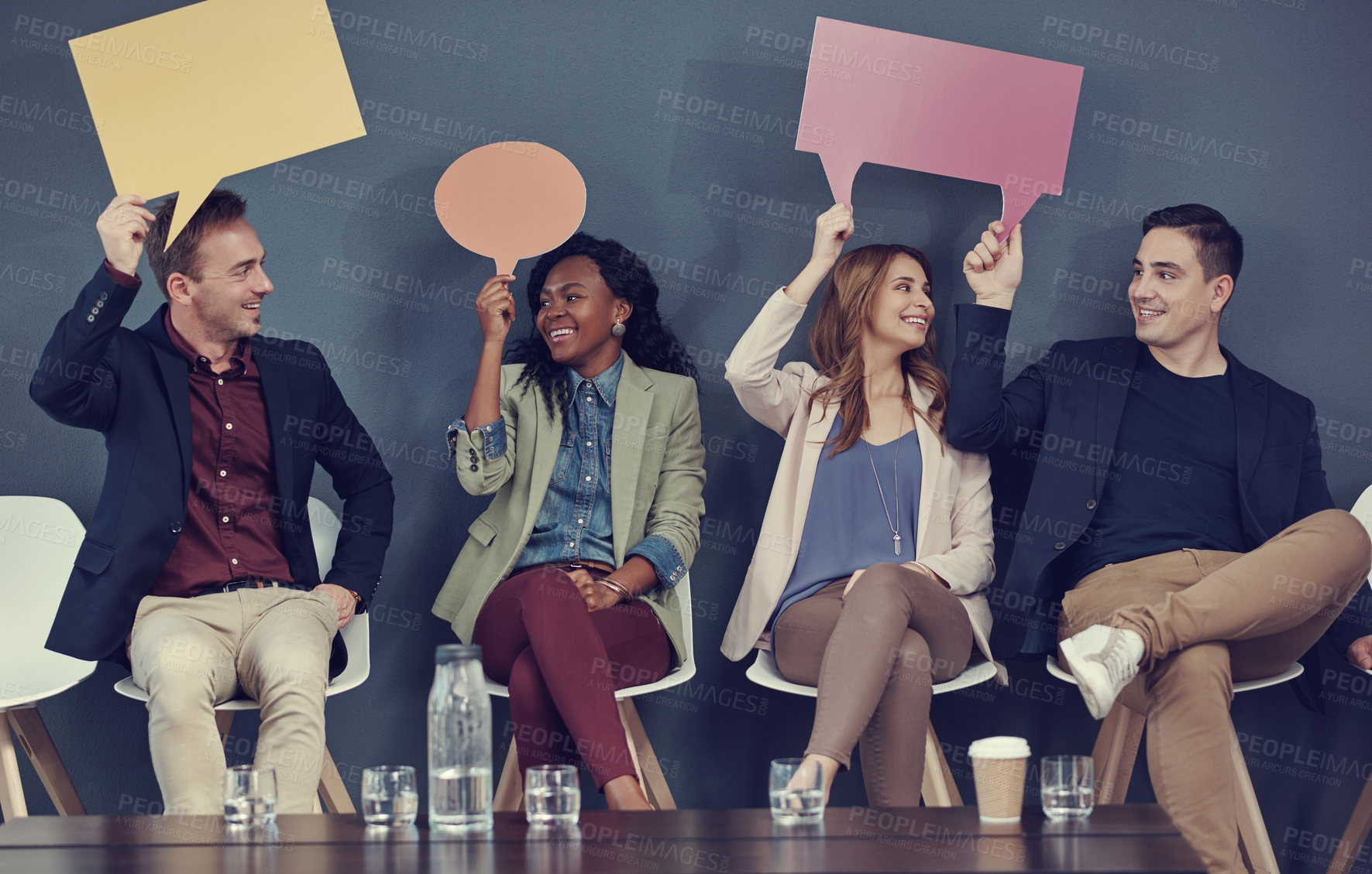 Buy stock photo Shot of a group of businesspeople holding up speech bubbles while waiting in line for an interview