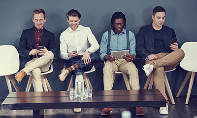 Buy stock photo Shot of a group of businessmen using different wireless devices while waiting in line for an interview