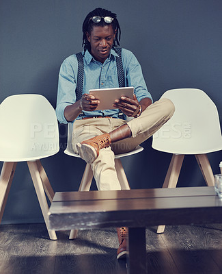 Buy stock photo Shot of a young businessman using a tablet while waiting for an interview