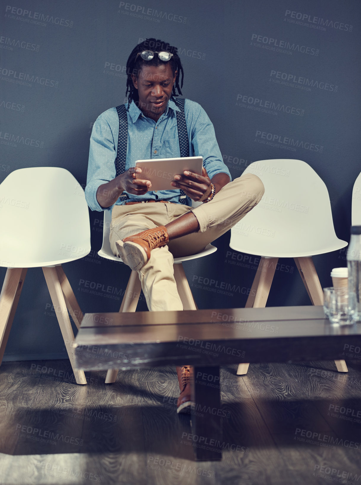 Buy stock photo Shot of a young businessman using a tablet while waiting for an interview