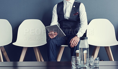 Buy stock photo Shot of an unrecognizable businessman using a tablet while waiting for an interview
