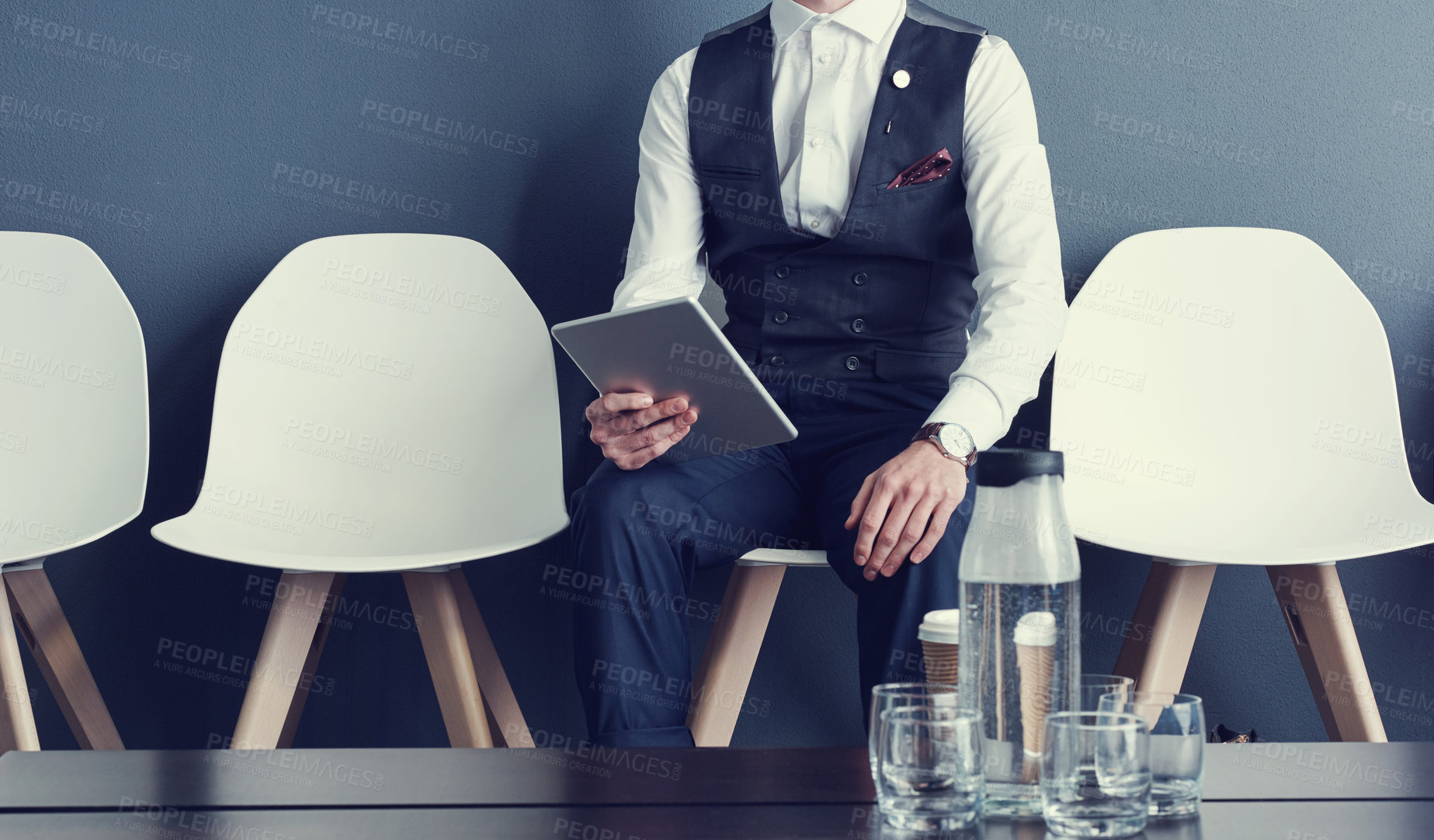 Buy stock photo Shot of an unrecognizable businessman using a tablet while waiting for an interview