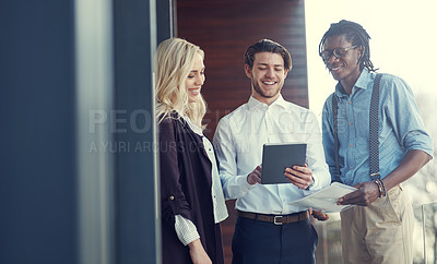 Buy stock photo Cropped shot of three young businesspeople using a tablet while standing outside on the office balcony