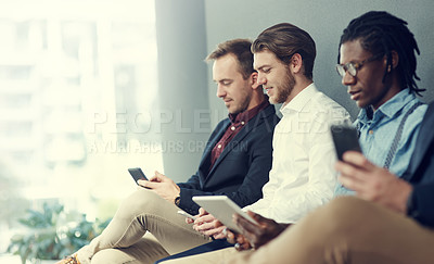 Buy stock photo Shot of a group of businessmen using different wireless devices while waiting in line for an interview