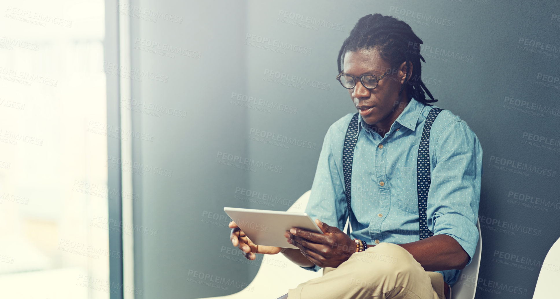 Buy stock photo Shot of a young businessman using a tablet while waiting for an interview