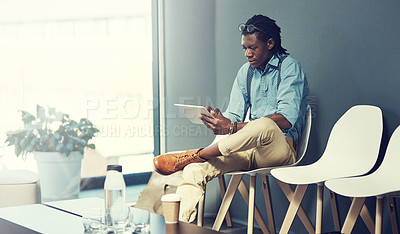 Buy stock photo Shot of a young businessman using a tablet while waiting for an interview