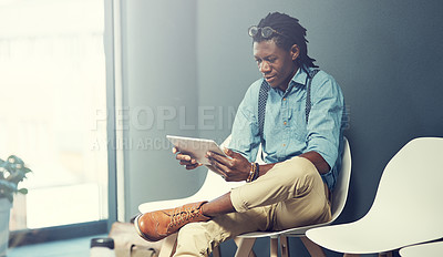 Buy stock photo Shot of a young businessman using a tablet while waiting for an interview