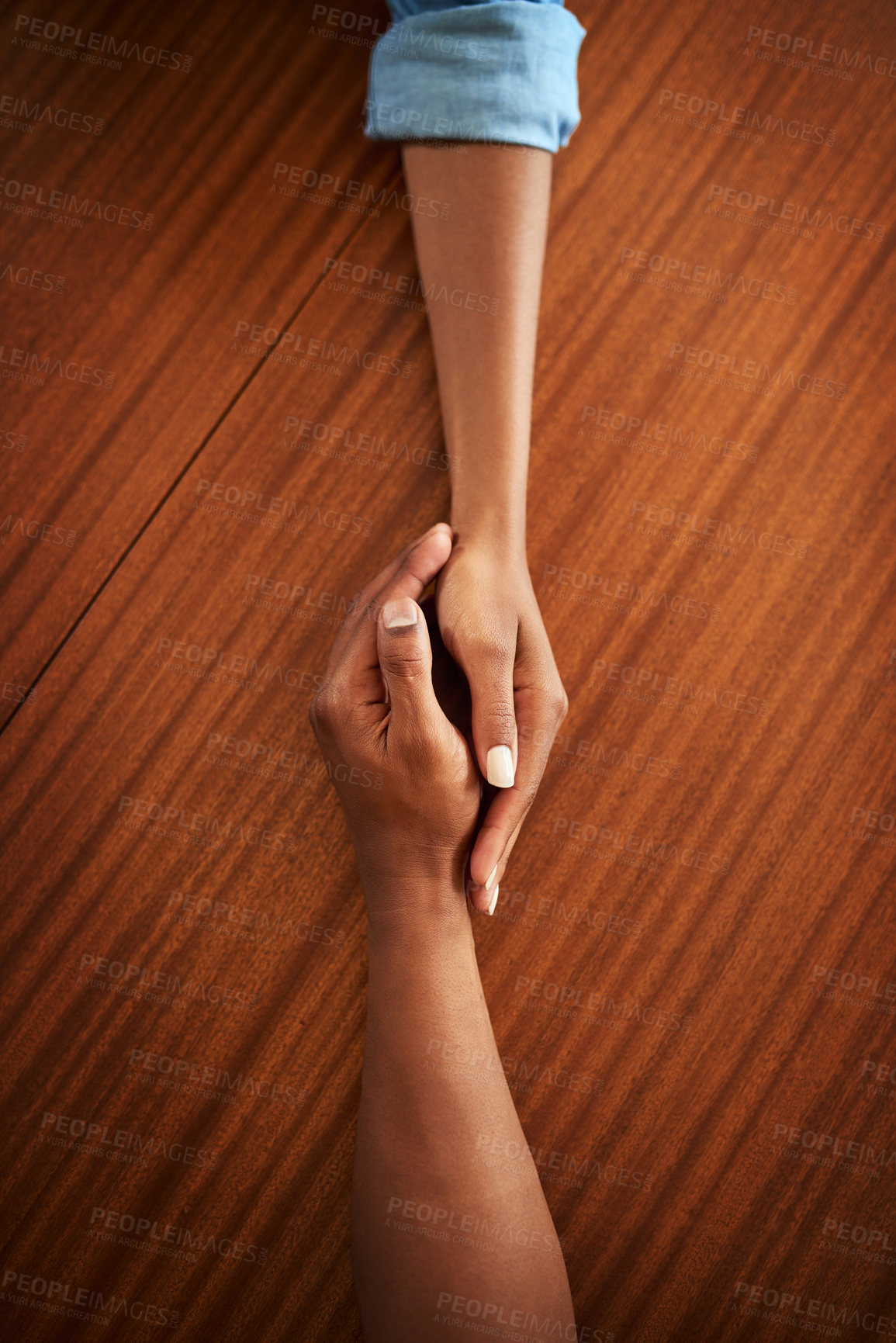 Buy stock photo High angle shot of two unrecognizable people's hands holding each other while resting on top of a wooden table