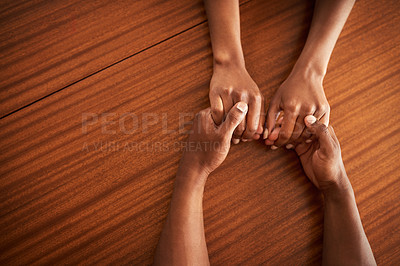 Buy stock photo High angle shot of two unrecognizable people's hands holding each other while resting on top of a wooden table