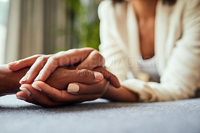 Buy stock photo Closeup of two unrecognizable people's hands holding each other while resting on top of a table