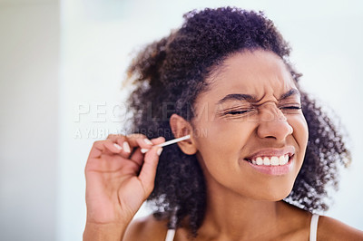 Buy stock photo Shot of an attractive young woman cleaning her ears with a cotton bud during her morning routine at home