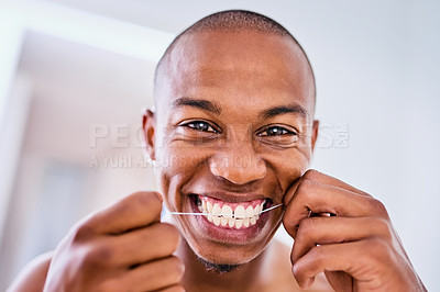 Buy stock photo Shot of an attractive young man flossing his teeth in the bathroom at home