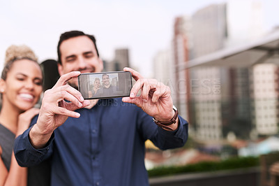 Buy stock photo Shot of two colleagues taking a selfie together outside an office