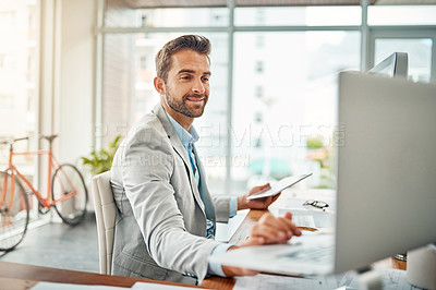 Buy stock photo Shot of a handsome young businessman working on a laptop and digital tablet in an office