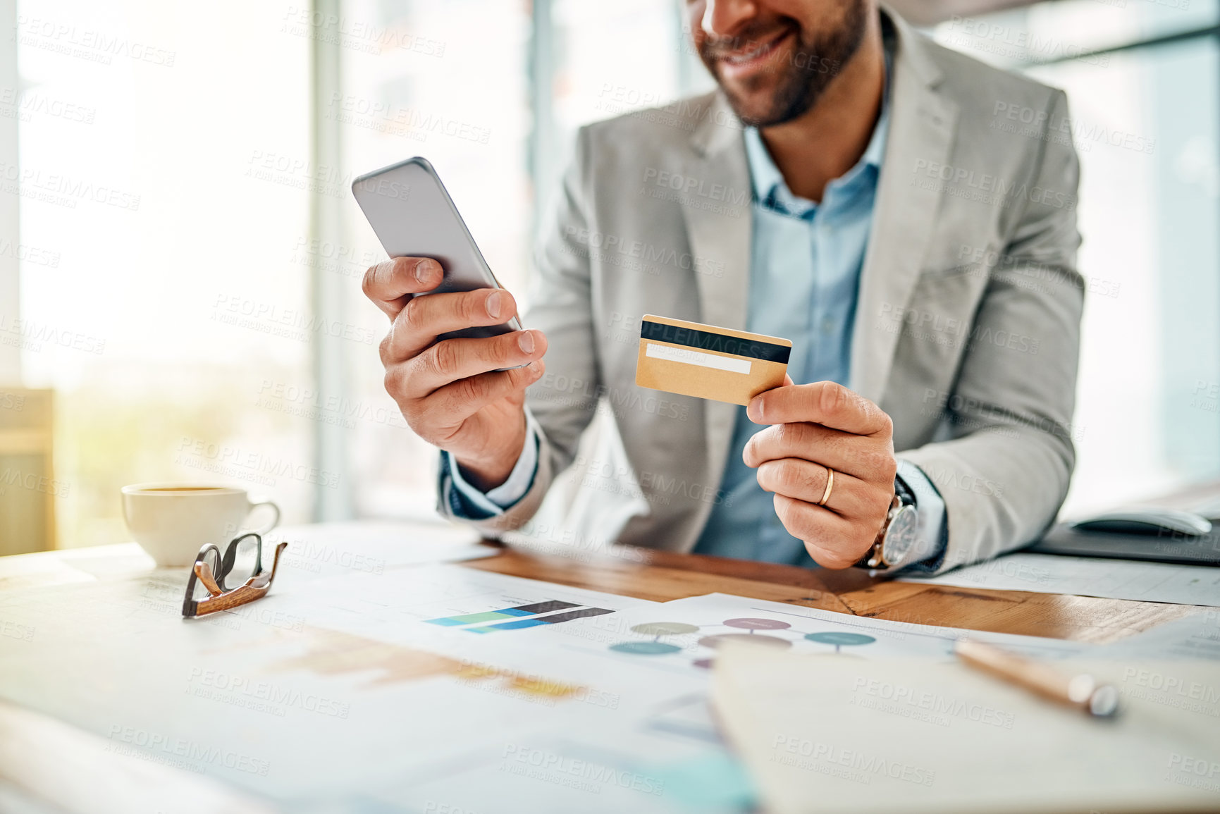 Buy stock photo Closeup shot of an unrecognizable businessman using a cellphone while holding a credit card in an office