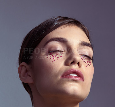 Buy stock photo Studio shot of an attractive young woman with gems under her eyes posing against a purple background