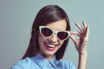 Buy stock photo Studio portrait of an attractive young woman posing with with stylish shades against a grey background