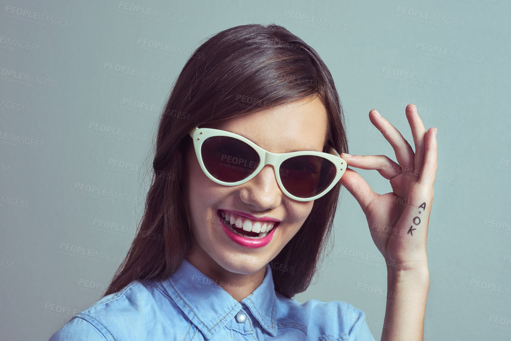 Buy stock photo Studio portrait of an attractive young woman posing with with stylish shades against a grey background