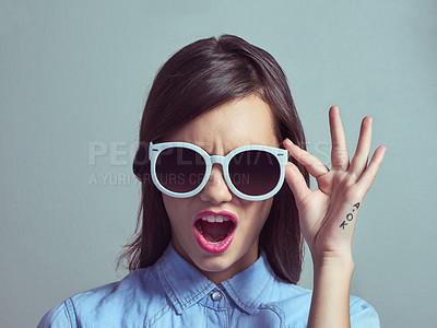 Buy stock photo Studio portrait of an attractive young woman looking shocked while wearing shades against a grey background