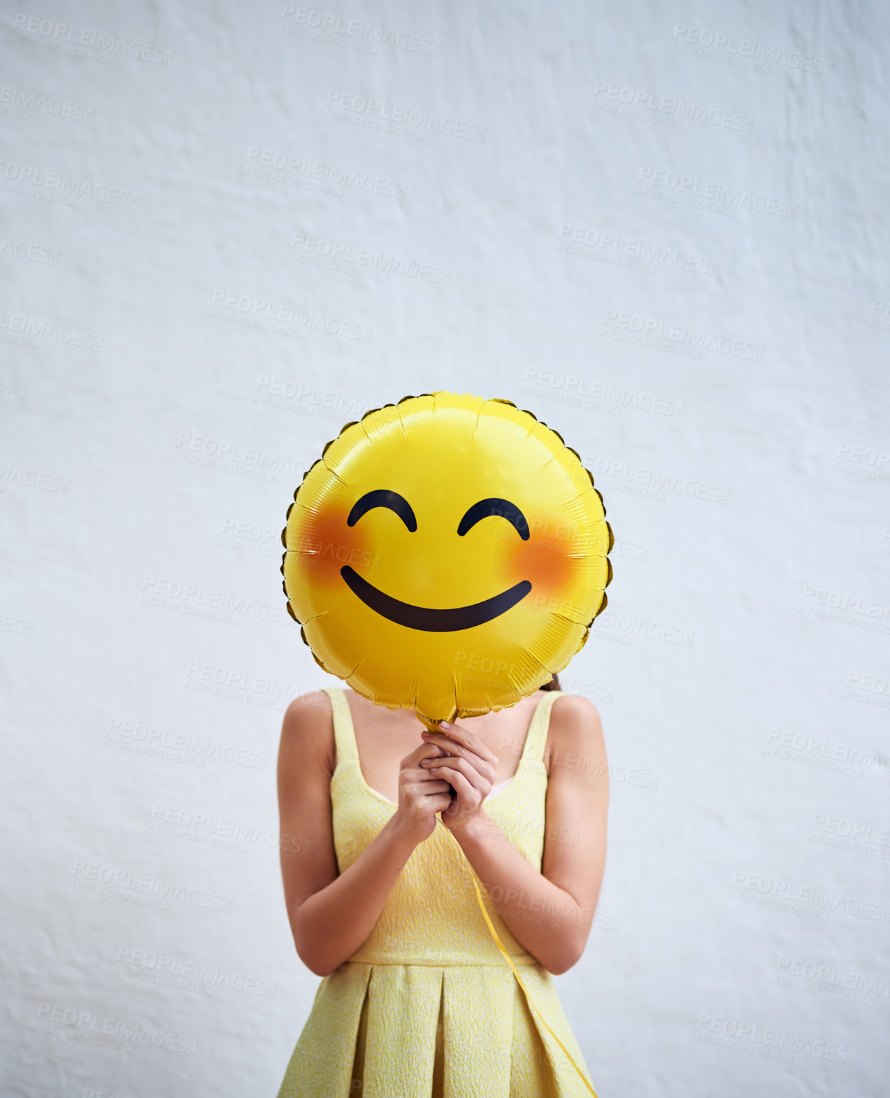 Buy stock photo Studio shot of an unrecognizable woman holding a smiling emoticon balloon in front of her face against a grey background