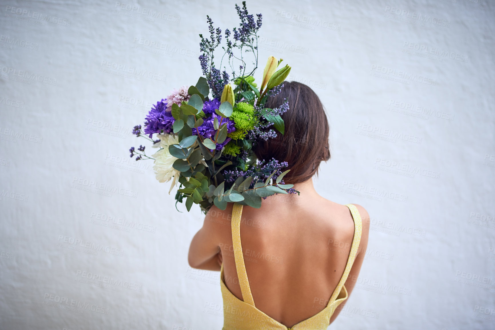 Buy stock photo Rearview studio shot of an unrecognizable woman holding a bouquet of flowers while standing against a grey background