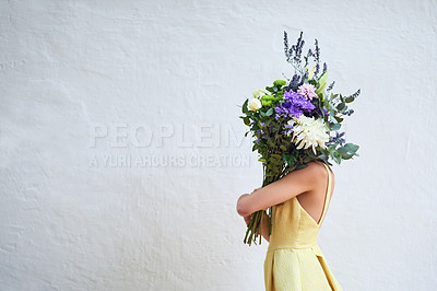 Buy stock photo Studio shot of an unrecognizable woman holding a bouquet of flowers while standing against a grey background