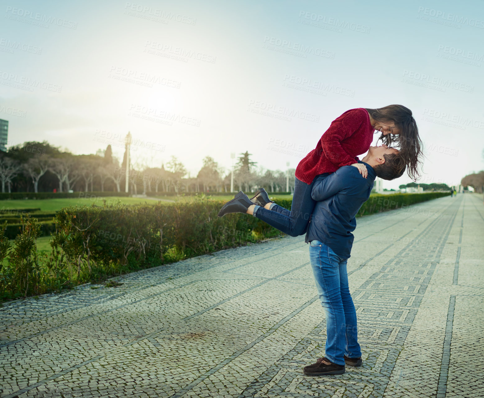 Buy stock photo Shot of a young man romantically carrying his girlfriend outdoors