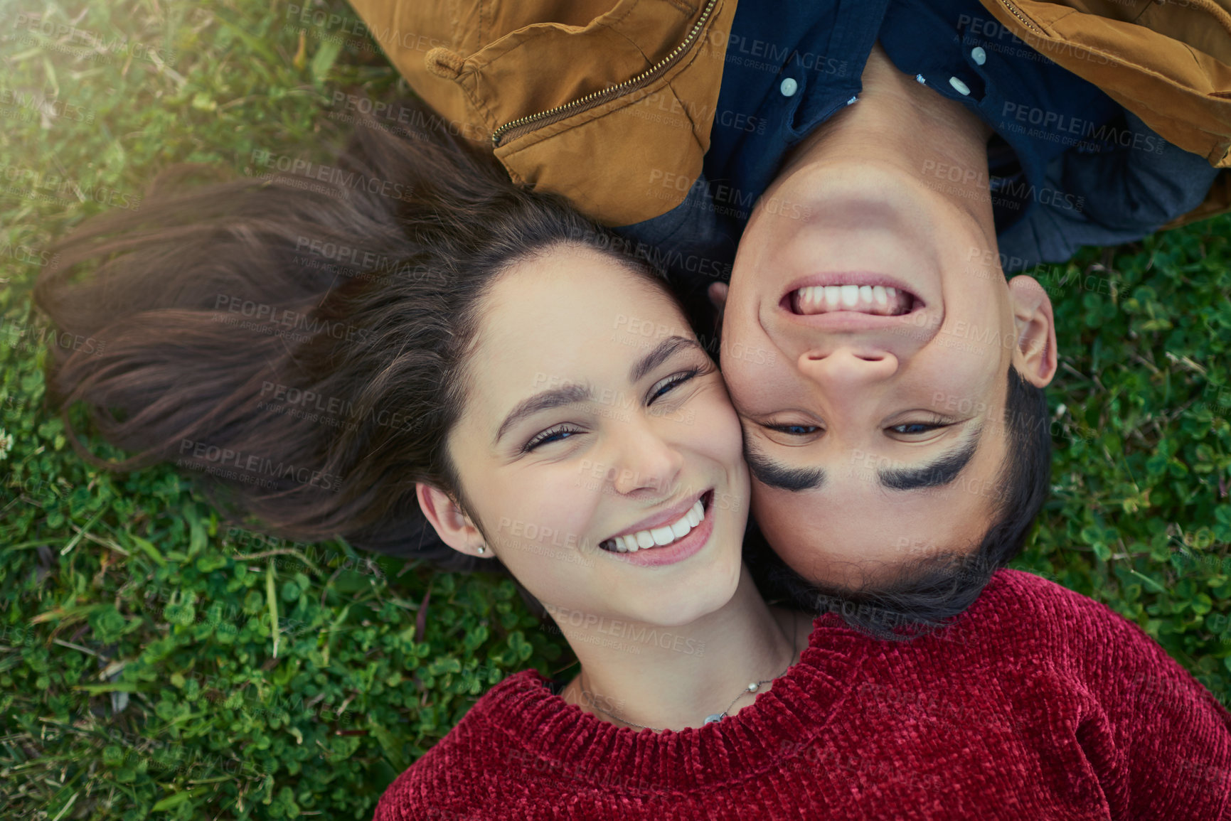 Buy stock photo High angle shot of a happy young couple laying together on the grass