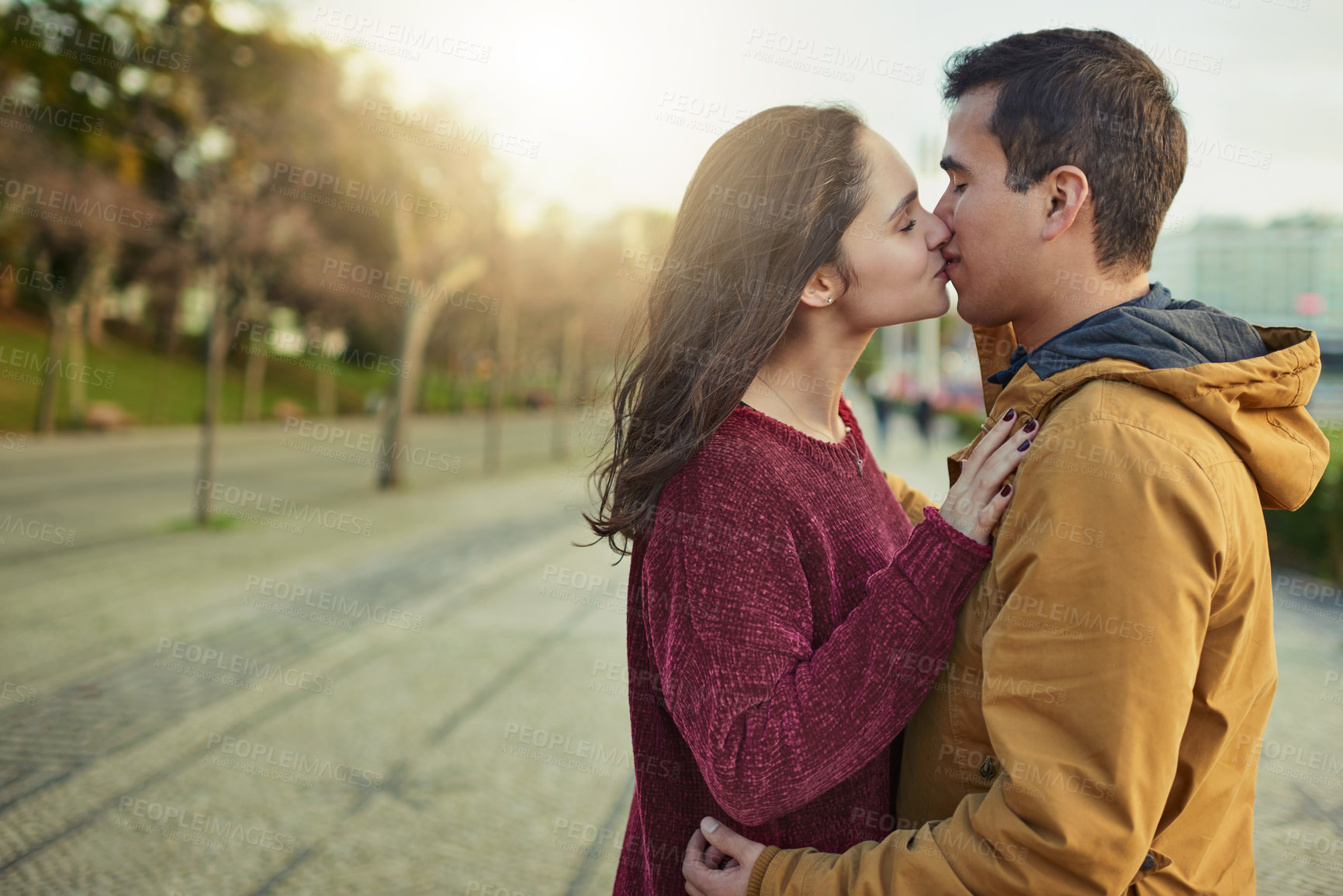 Buy stock photo Shot of a happy young couple kissing each other outdoors