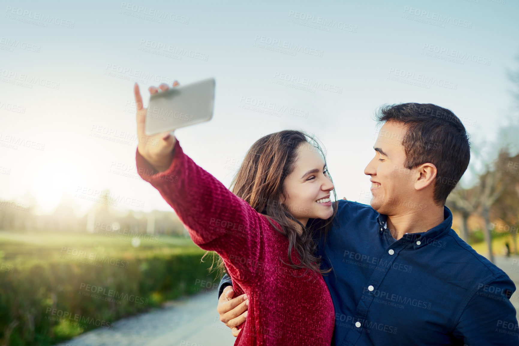 Buy stock photo Shot of a happy young couple taking a selfie outdoors