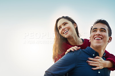 Buy stock photo Shot of a happy young couple enjoying a piggyback ride outdoors