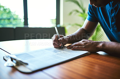 Buy stock photo Closeup shot of an unrecognizable man filling in paperwork at a table