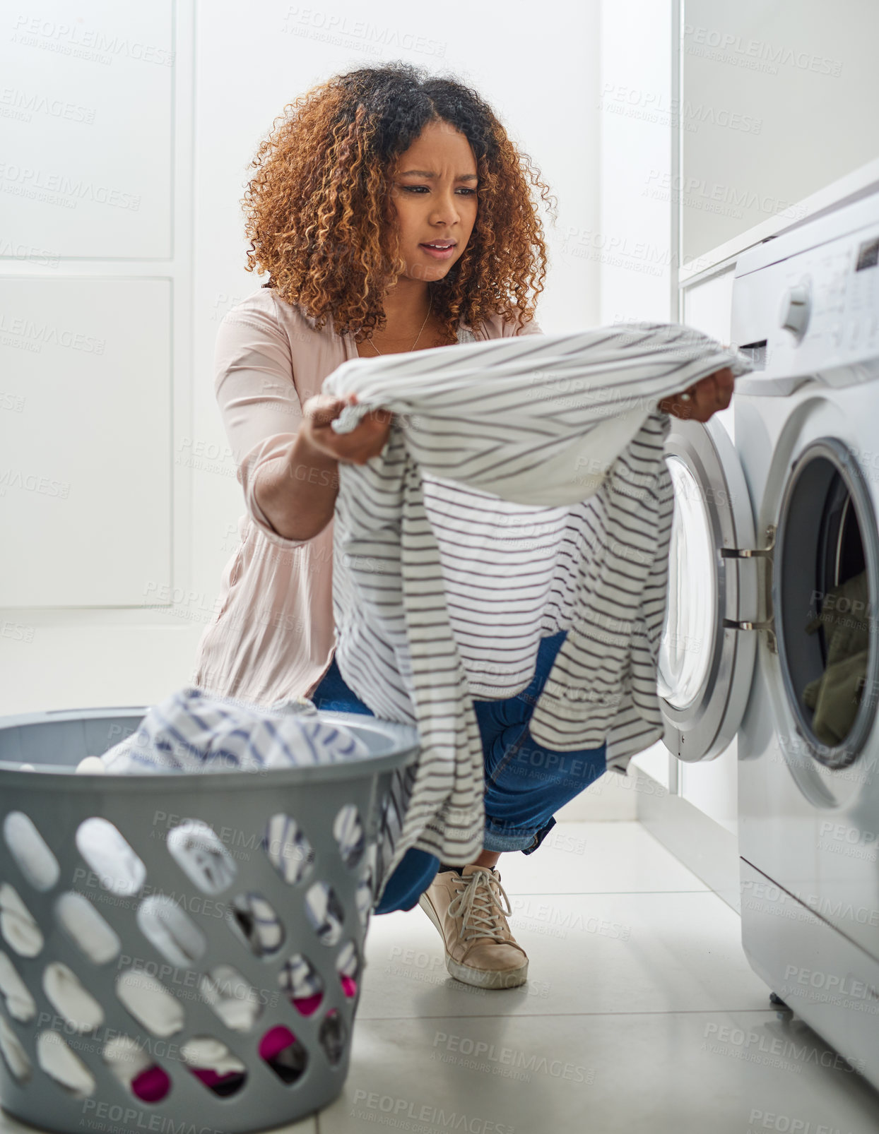 Buy stock photo Shot of a young attractive woman doing laundry at home