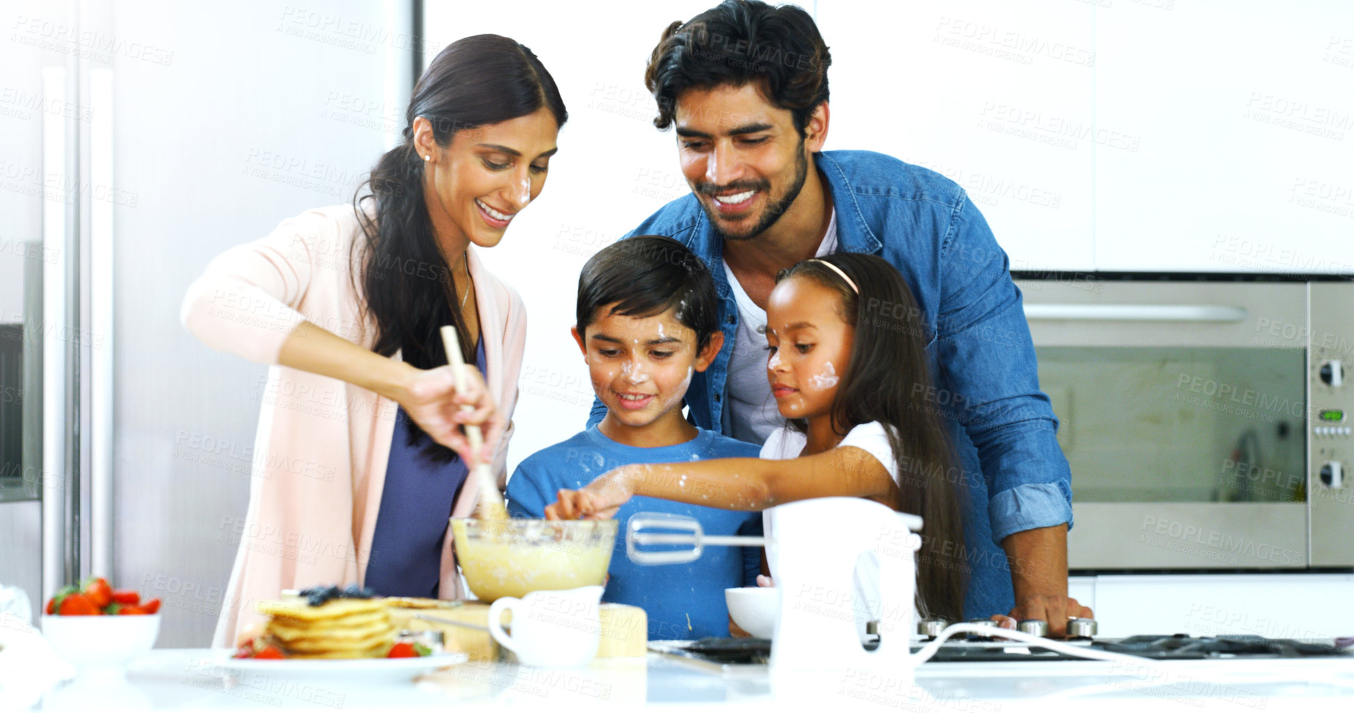 Buy stock photo Shot of a young family making pancakes together in the kitchen at home