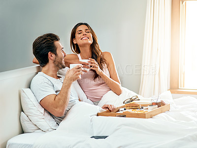 Buy stock photo Shot of a happy young couple enjoying breakfast in bed together at home