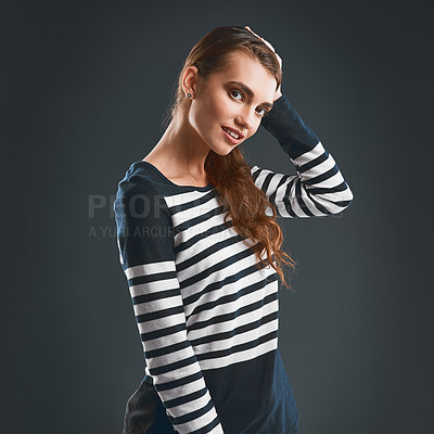 Buy stock photo Studio portrait of a cheerful young woman holding the side of her head while standing against a dark background
