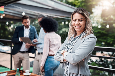 Buy stock photo Portrait of a confident young businesswoman standing outside with her colleagues in the background