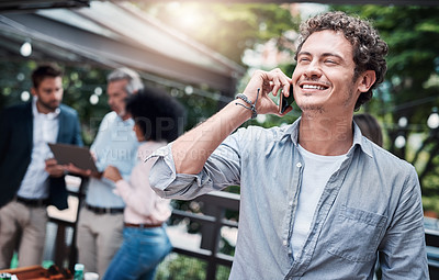Buy stock photo Shot of a businessman talking on a cellphone outside with his colleagues in the background