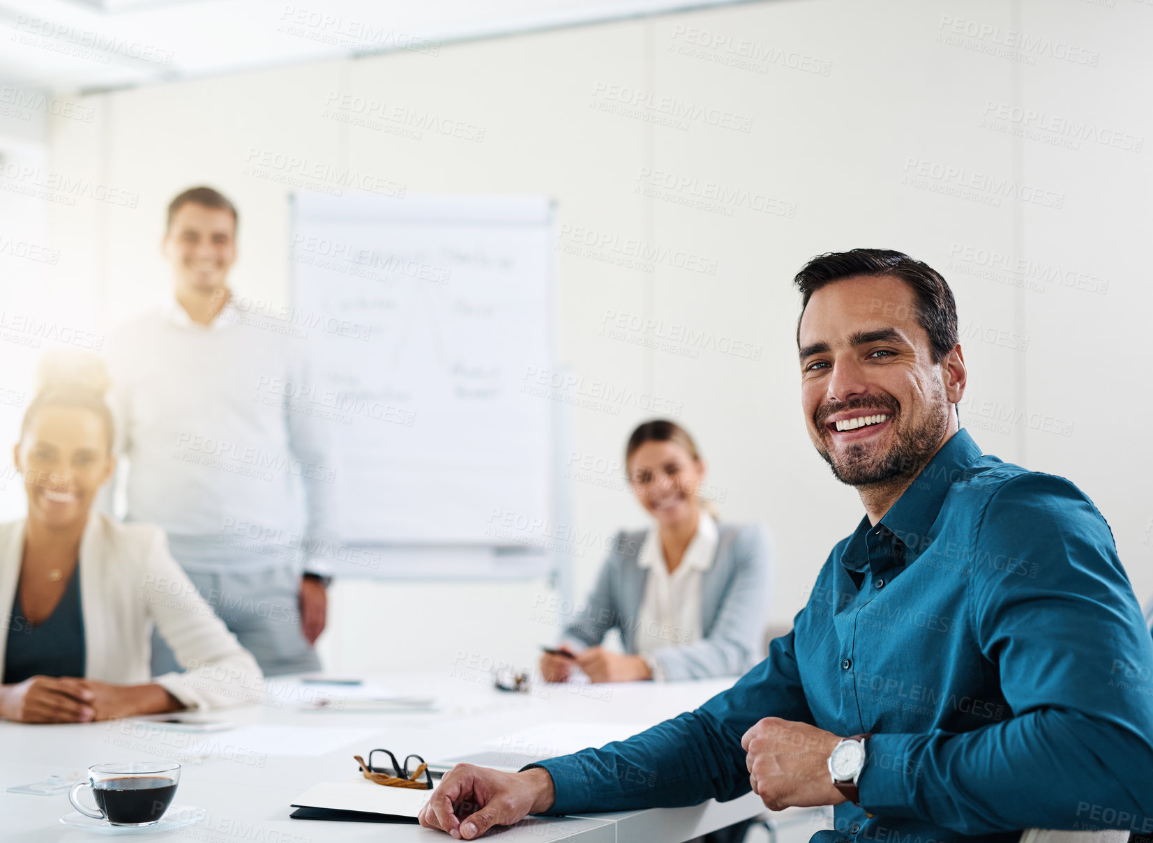 Buy stock photo Portrait of a young businessman having a meeting with his colleagues in an office