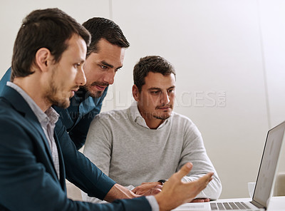 Buy stock photo Shot of a group of businessmen working together on a laptop in an office