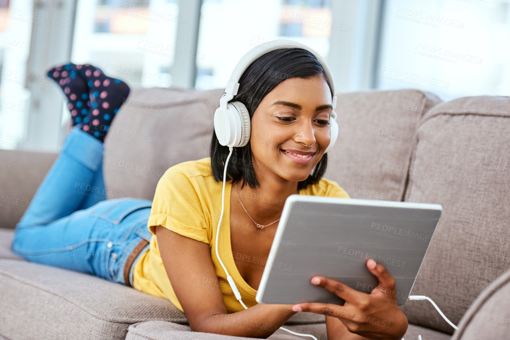 Buy stock photo Shot of a teenage girl listening to music and using a tablet at home