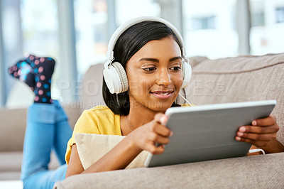 Buy stock photo Shot of a teenage girl listening to music and using a tablet at home