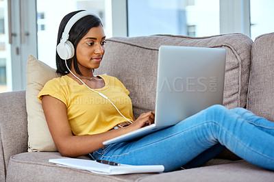 Buy stock photo Shot of a teenage girl listening to music and using a laptop at home