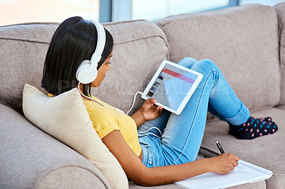 Buy stock photo Girl, home and tablet on headphones with writing on notebook for studying, revision and research. Female person, teenager and gen z on sofa in living room for motivational music, audio and radio