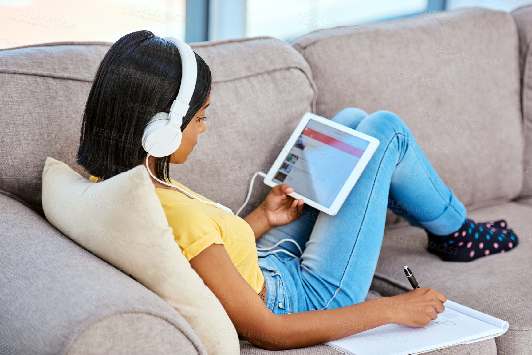 Buy stock photo Shot of a teenage girl listening to music and using a tablet at home