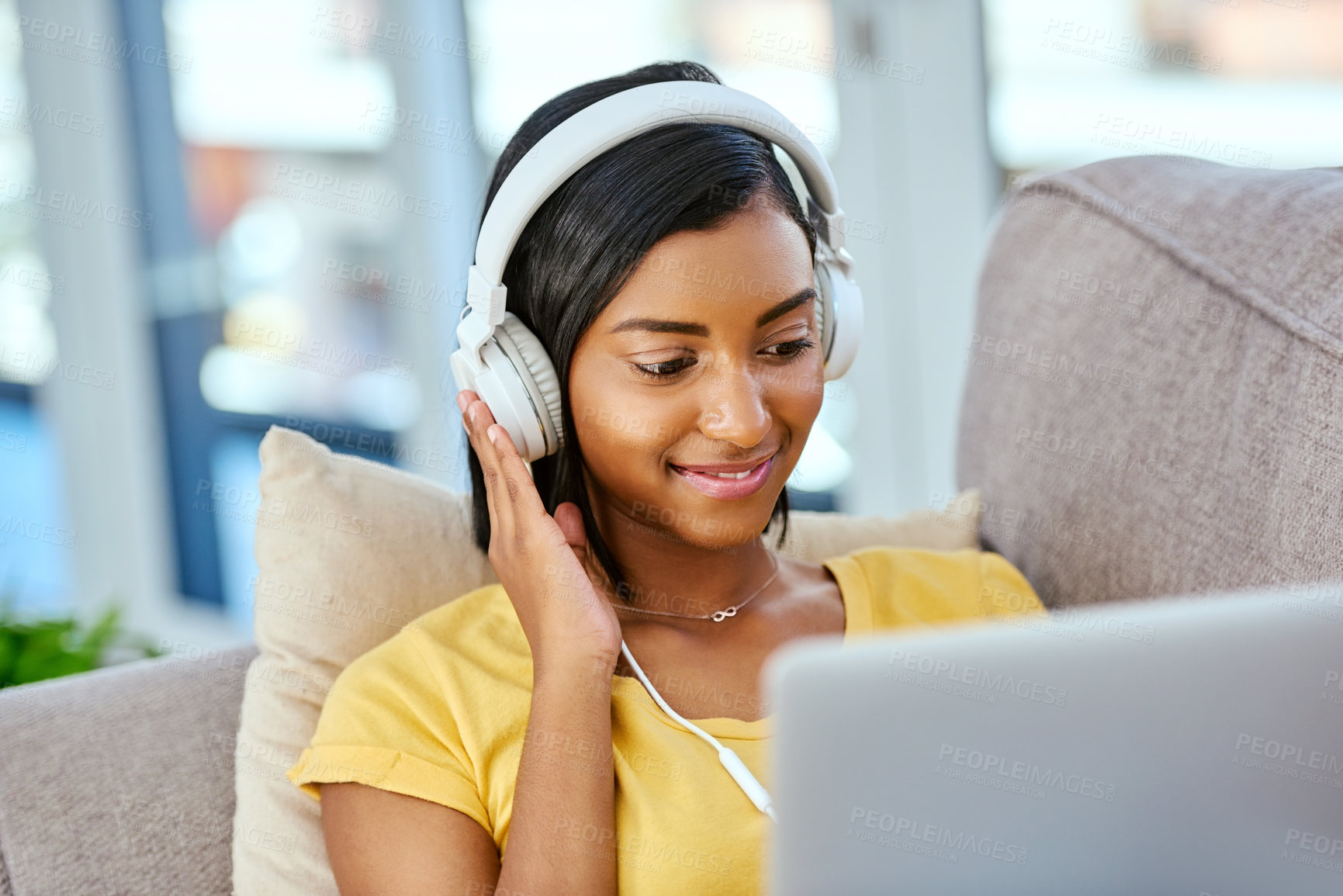 Buy stock photo Shot of a teenage girl listening to music and using a laptop at home