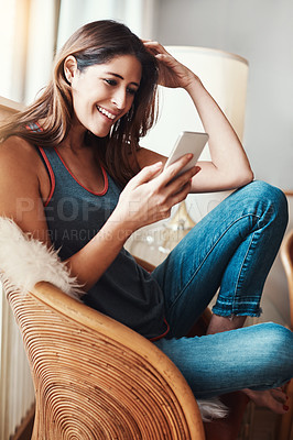 Buy stock photo Shot of an attractive young woman using her cellphone at home