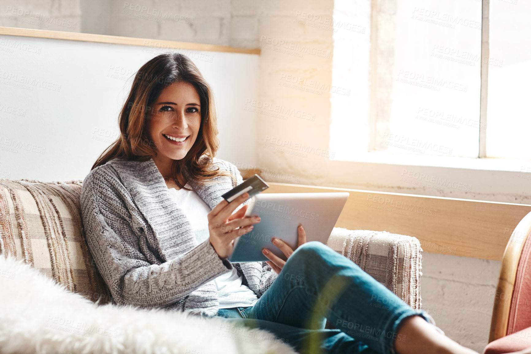 Buy stock photo Portrait of an attractive young woman using a digital tablet and credit card on the sofa at home