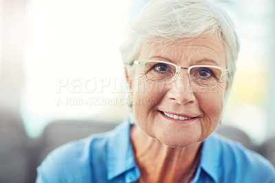 Buy stock photo Cropped portrait of a senior woman sitting on her sofa at home