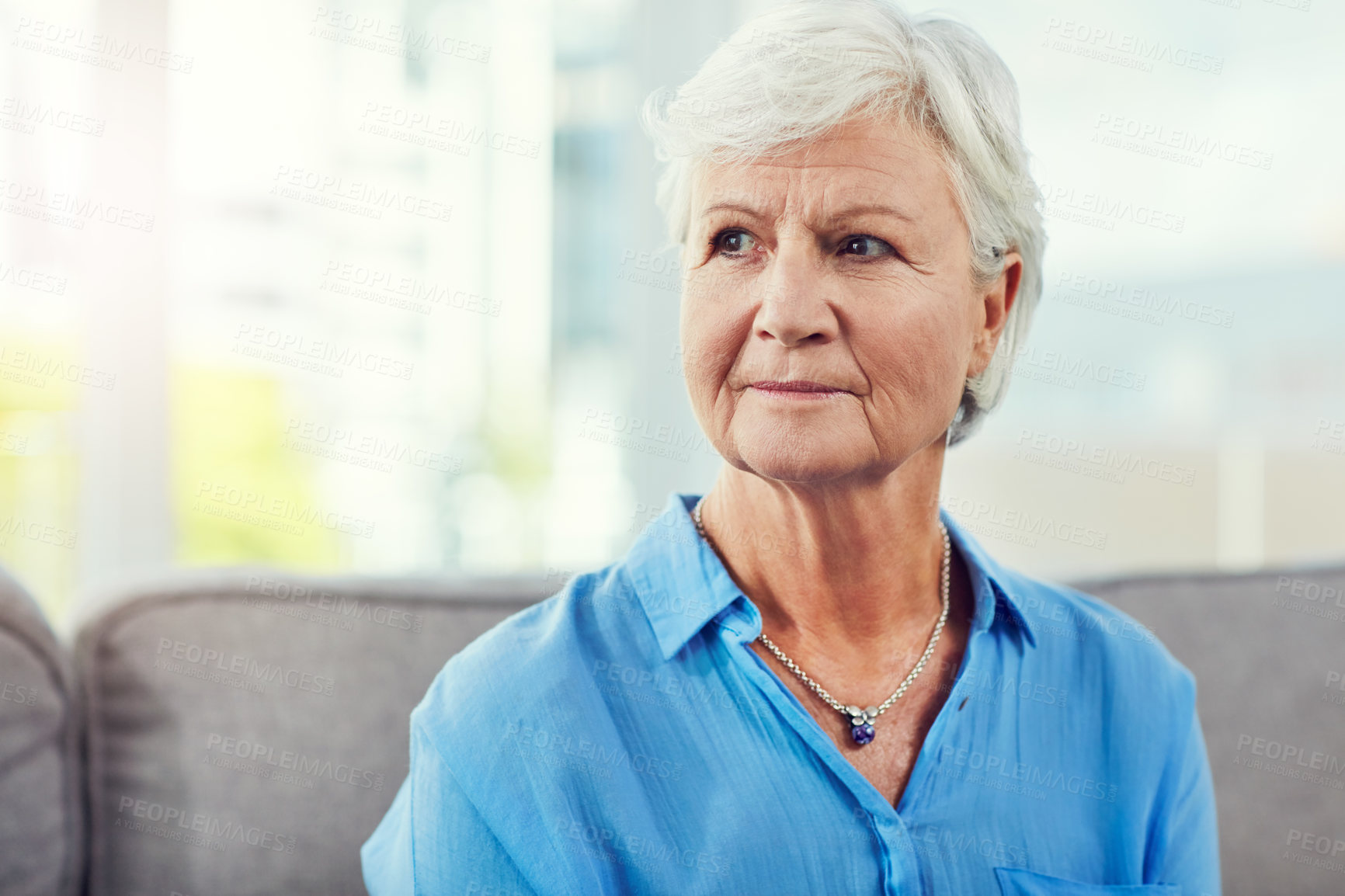 Buy stock photo Cropped shot of a senior woman sitting on her sofa at home